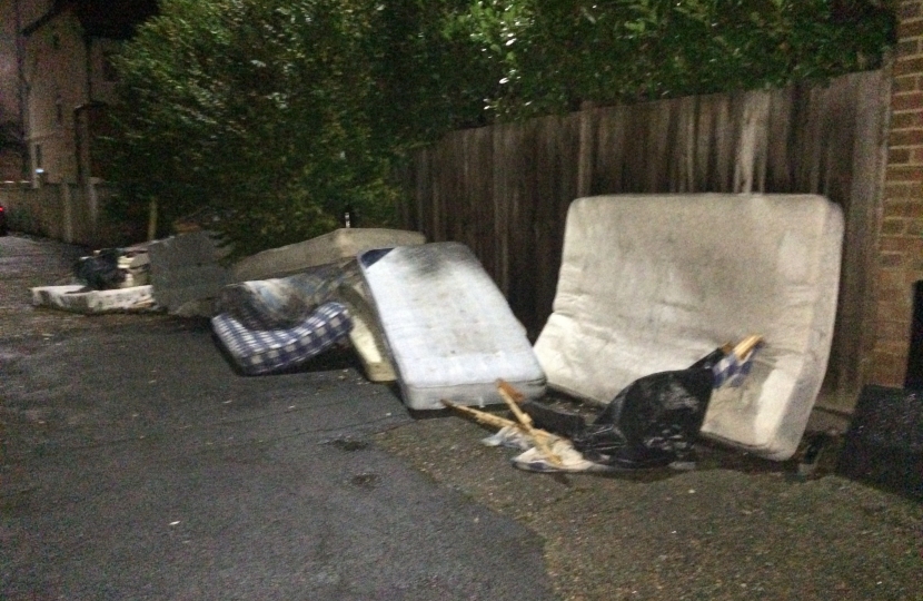 A spread out slew of filthy mattresses dumped on a road