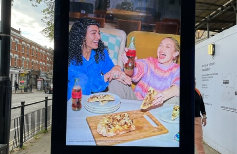 Advert for Coca Cola showing two female friends looking joyous eating pizza and drinking Coke