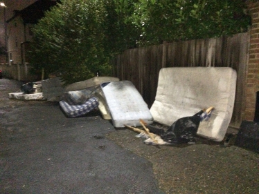 A spread out slew of filthy mattresses dumped on a road