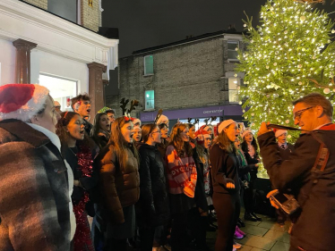 Chiswick School students singing The Twelve Days of Christmas next to the beautiful just-lit Christmas tree 